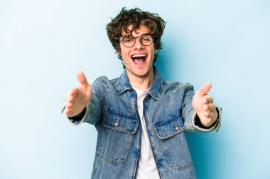 Mavi arka planda izole edilmiş beyaz bir genç hoş bir yüz ifadesi sergiliyor..