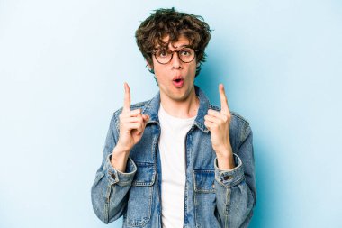 Mavi arka planda izole edilmiş beyaz bir adam ağzı açık bir şekilde üst tarafı işaret ediyor..