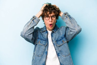 Kafkasyalı genç adam mavi arka planda izole edildi. Şaşırdı ve şok oldu..