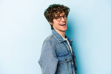 Kafkasyalı genç, mavi arka planda izole edilmiş. Kendine güvenen, kalçaları tutan biri..