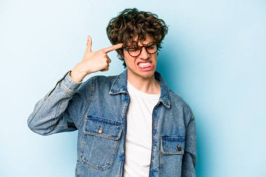 Mavi arka planda izole edilmiş genç beyaz adam kulaklarını elleriyle kapatıyor..