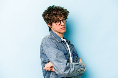 Kafkasyalı genç adam mavi arka planda izole edilmiş şüpheli, belirsiz, seni muayene ediyor..