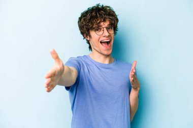 Mavi arka planda izole edilmiş genç beyaz adam kameraya sarıldığı için kendinden emin hissediyor..