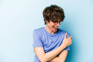 Kafkasyalı genç adam mavi arka planda izole edilmiş gülüyor ve eğleniyor..