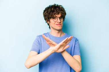 Kafkasyalı genç adam mavi arka planda izole edilmiş bir şekilde inkar hareketi yapıyor.