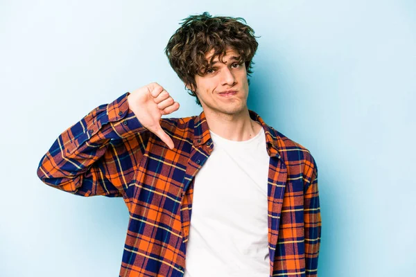 Mavi arka planda izole edilmiş genç beyaz bir adam hoşlanmadığı bir jest yapıyor. Anlaşmazlık konsepti.