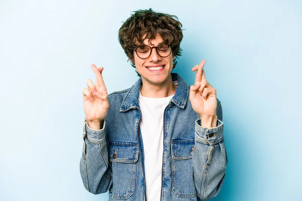 Kafkasyalı genç adam mavi arka planda izole edilmiş şans dilemek için şans diliyor.