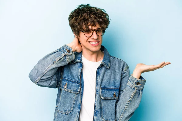 Mavi arka planda izole edilmiş genç beyaz adam öfkeyle bağırıyor..