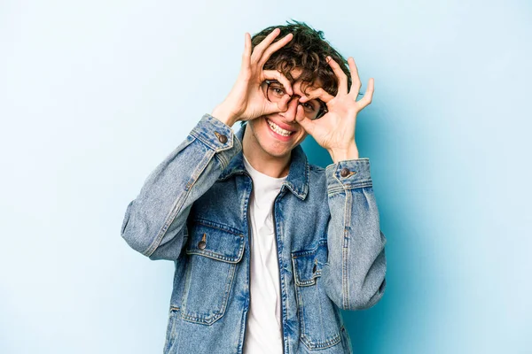 Kafkasyalı genç adam mavi arka planda izole edildi. Heyecanlı görünüyor..