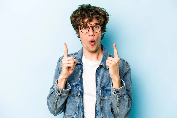 Mavi arka planda izole edilmiş beyaz bir adam ağzı açık bir şekilde üst tarafı işaret ediyor..