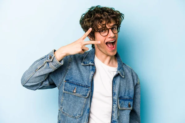 Genç beyaz adam mavi arka planda izole edilmiş dans ediyor ve eğleniyor..