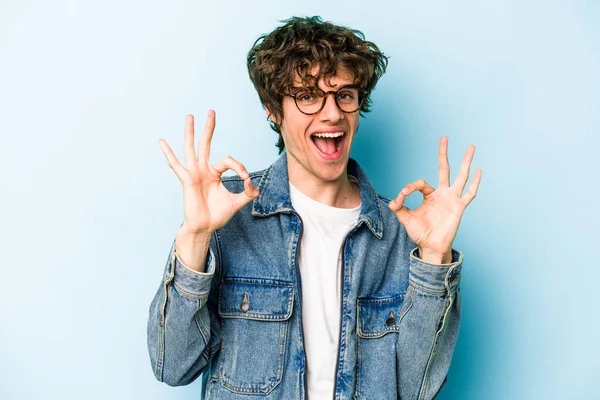 Kafkasyalı genç adam mavi arka planda izole edilmiş neşeli ve kendinden emin..