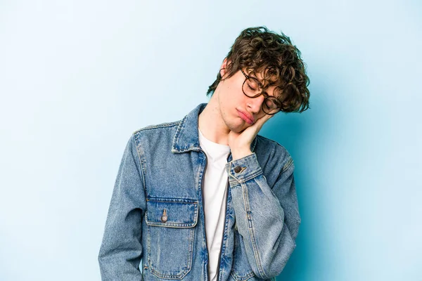 Mavi arka planda izole edilmiş, sıkılmış, yorgun ve dinlenmeye ihtiyacı olan genç beyaz bir adam..