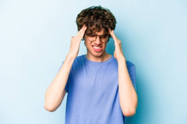 Kafkasyalı genç bir adam mavi arka planda izole edilmiş, başı ağrıyor, yüzüne dokunuyor..