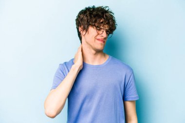 Kafkasyalı genç adam mavi arka planda izole edilmiş dirsek masajı yapıyor, kötü bir hareketin ardından acı çekiyor..