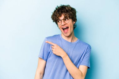 Mavi arka planda soyutlanmış genç beyaz bir adam gülümsüyor, neşeli ve keyifli görünüyor..