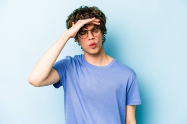 Genç beyaz adam mavi arka planda izole edilmiş tapınaklara dokunuyor ve başı ağrıyor..