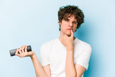 Elinde televizyon kumandası olan beyaz bir adam mavi arka planda izole edilmiş.