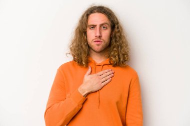 Beyaz arka planda izole edilmiş genç beyaz adam yemin ediyor, elini göğsüne koyuyor..