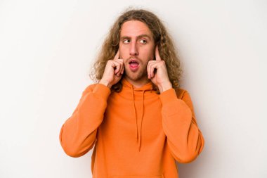 Beyaz arka planda izole edilmiş genç beyaz bir adam parmaklarıyla kulaklarını kapatıyor, gürültülü bir ortam yüzünden stresli ve çaresiz..