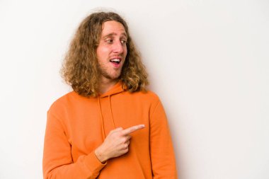 Beyaz arka planda izole edilmiş genç beyaz adam gülümseyen, neşeli ve keyifli bir tarafa bakıyor..