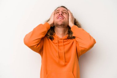 Beyaz arka planda izole olmuş genç beyaz bir adam ellerini başının üstünde tutarak neşeyle gülüyor. Mutluluk kavramı.