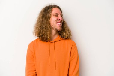 Beyaz arka planda izole edilmiş genç beyaz adam gevşemiş ve mutlu bir şekilde gülüyor, boynunda dişlerini gösteriyor..