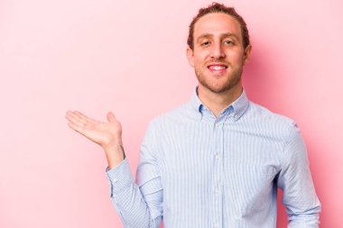 Pembe arka planda izole edilmiş genç beyaz bir adam bir palmiye üzerinde fotokopi alanı ve belinde başka bir el tutuyor..