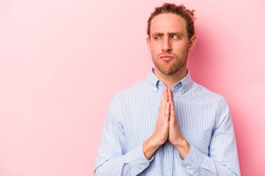 Kafkasyalı genç bir adam pembe arka planda izole edilmiş bir plan yapıyor, bir fikir kuruyor..