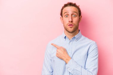 Pembe arka planda izole edilmiş genç beyaz adam yan tarafı gösteriyor.