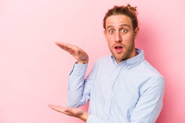 Pembe arka planda izole edilmiş genç beyaz adam elleri arasında bir fotokopi alanı tutuyor..