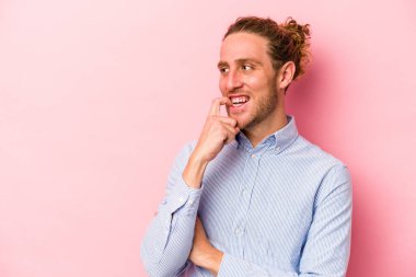 Pembe arka planda izole edilmiş genç beyaz adam rahatlamış bir şeyin fotokopi odasına baktığını düşünüyor..