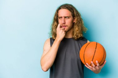 Basketbol oynayan beyaz bir adam mavi arka planda izole edilmiş bir şekilde rahat bir şekilde fotokopi odasına bakan bir şeyi düşünüyor..