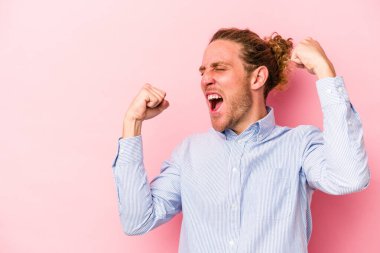 Pembe arka planda izole edilmiş genç beyaz adam zaferden sonra yumruğunu kaldırıyor, kazanan konsept..