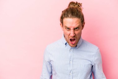 Pembe arka planda izole edilmiş genç beyaz adam çok kızgın, öfkeli, hayal kırıklığına uğramış diye bağırıyor..
