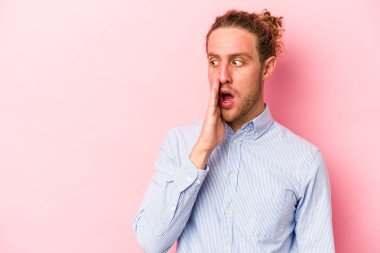 Pembe arka planda izole edilmiş genç beyaz adam gizli bir sıcak fren haberi veriyor ve yana bakıyor.