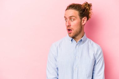 Pembe arka planda izole edilmiş genç beyaz adam gördüğü bir şey yüzünden şoka uğruyor..