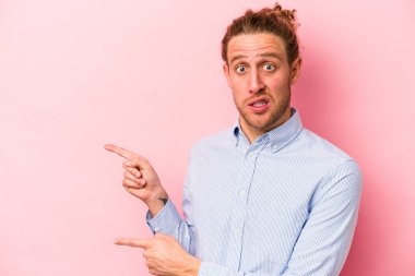 Pembe arka planda izole edilmiş genç beyaz adam işaret parmağıyla fotokopi alanını işaret ederek şok oldu..