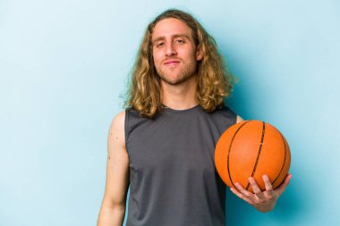 Basketbol oynayan beyaz bir adam mavi arka planda izole edilmiş mutlu, güler yüzlü ve neşeli..
