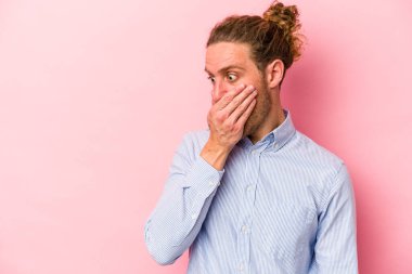 Pembe arka planda izole edilmiş genç beyaz bir adam. Düşünceli bir şekilde ağzıyla ağzını kapatan bir fotokopi odasına bakıyor..
