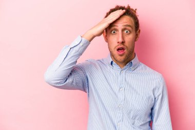 Pembe arka planda izole edilmiş genç beyaz adam yüksek sesle bağırıyor, gözleri açık ve elleri gergin tutuyor..