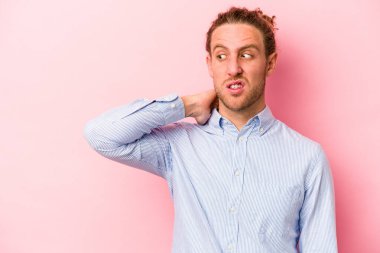 Kafkasyalı genç bir adam pembe arka planda izole edilmiş kafasının arkasına dokunuyor, düşünüyor ve bir seçim yapıyor..