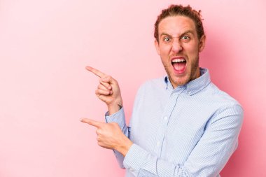 Pembe arka planda izole edilmiş genç beyaz adam işaret parmağıyla fotokopi alanını işaret ederek heyecan ve arzusunu ifade ediyor..