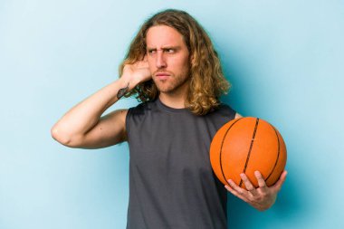Basketbol oynayan beyaz bir adam mavi arka planda izole edilmiş bir şekilde bir dedikoduyu dinlemeye çalışıyor..