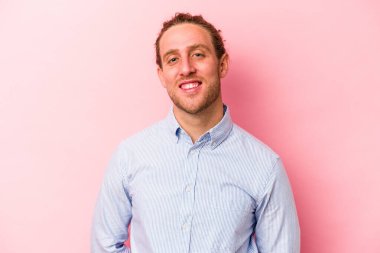 Pembe arka planda izole edilmiş genç beyaz adam mutlu, güler yüzlü ve neşeli.