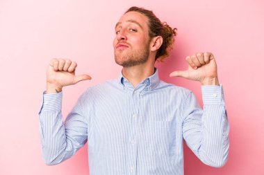 Pembe arka planda izole edilmiş genç beyaz adam gururlu ve kendinden emin hissediyor, örnek olarak.