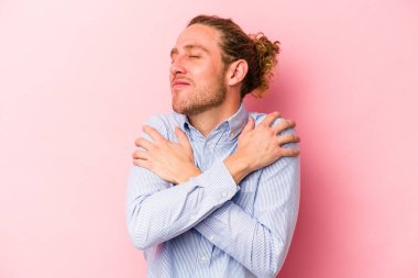 Kafkasyalı genç adam pembe arka planda izole edilmiş, güler yüzlü, kaygısız ve mutlu..