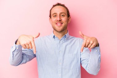 Pembe arka planda izole edilmiş genç beyaz adam parmaklarıyla aşağıya doğru, olumlu bir his..