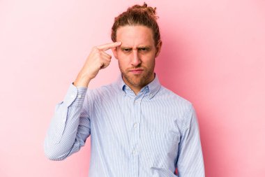 Pembe arka planda izole edilmiş genç beyaz bir adam parmağıyla tapınağı işaret ediyor, düşünüyor ve bir göreve odaklanıyor..