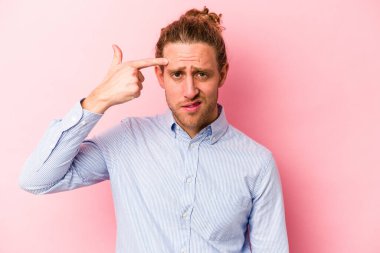 Pembe arka planda izole edilmiş genç beyaz adam işaret parmağıyla hayal kırıklığı jesti gösteriyor..